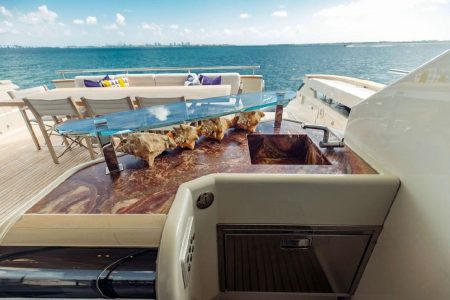 Luxury 110ft Dominator Senay Miami grand boarding entrance with access to the upper deck with spacious table with chairs and bar for drinks.